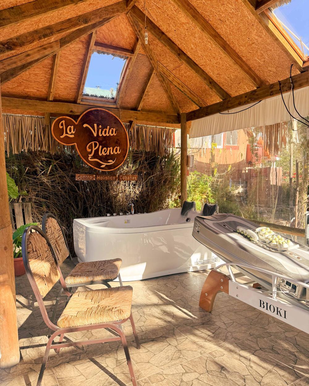 Espacio de bienestar bajo techo de madera con jacuzzi y cama Bioki