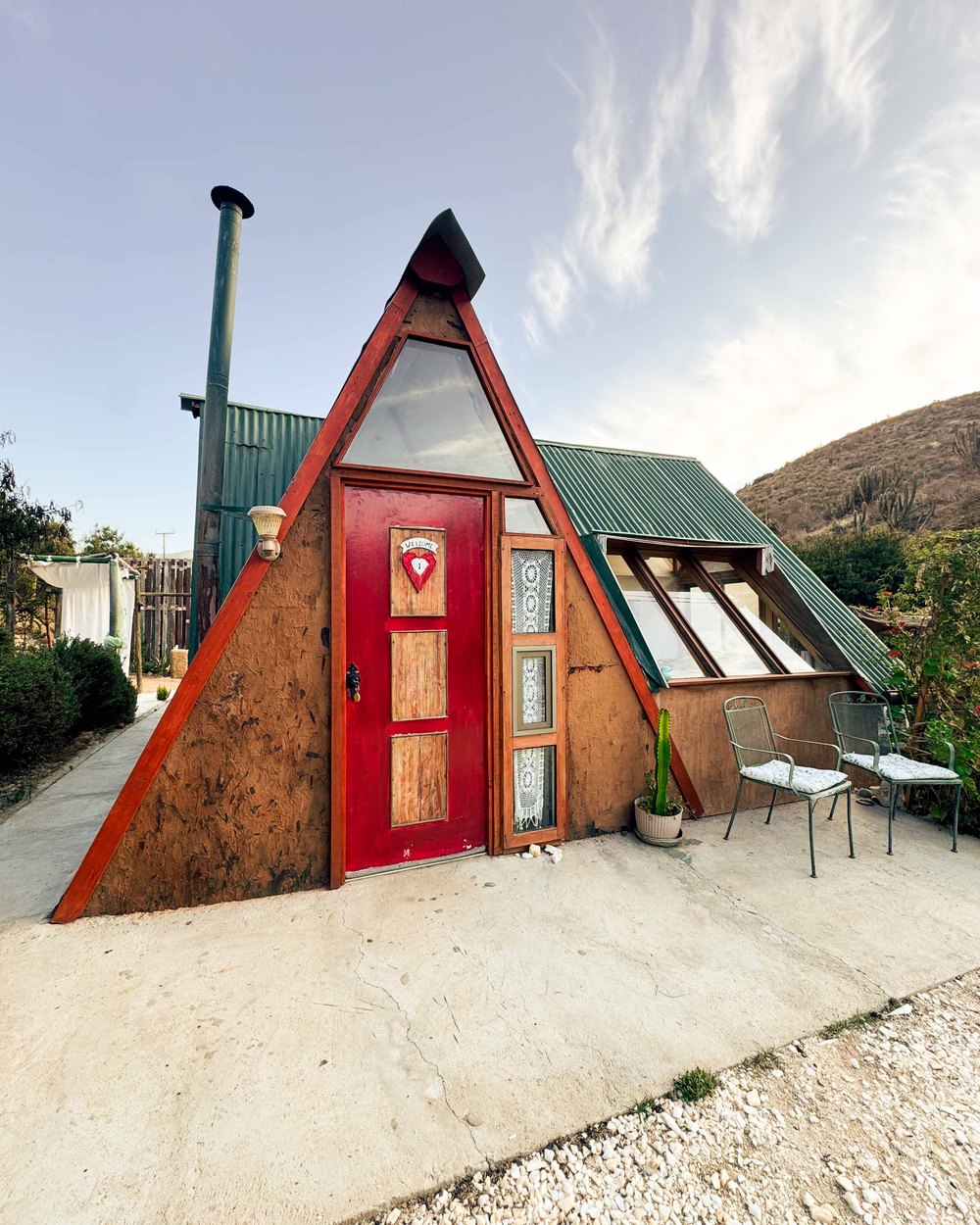 Fachada de la cabaña con puerta roja y ventanal